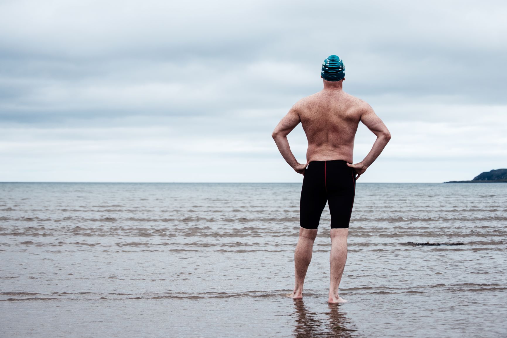 Man standing on sea shore ready to swim