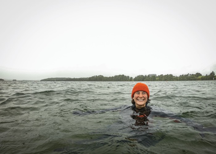 Kerri ni Dochartaigh floating in the rainy sea with an orange woolly hat on